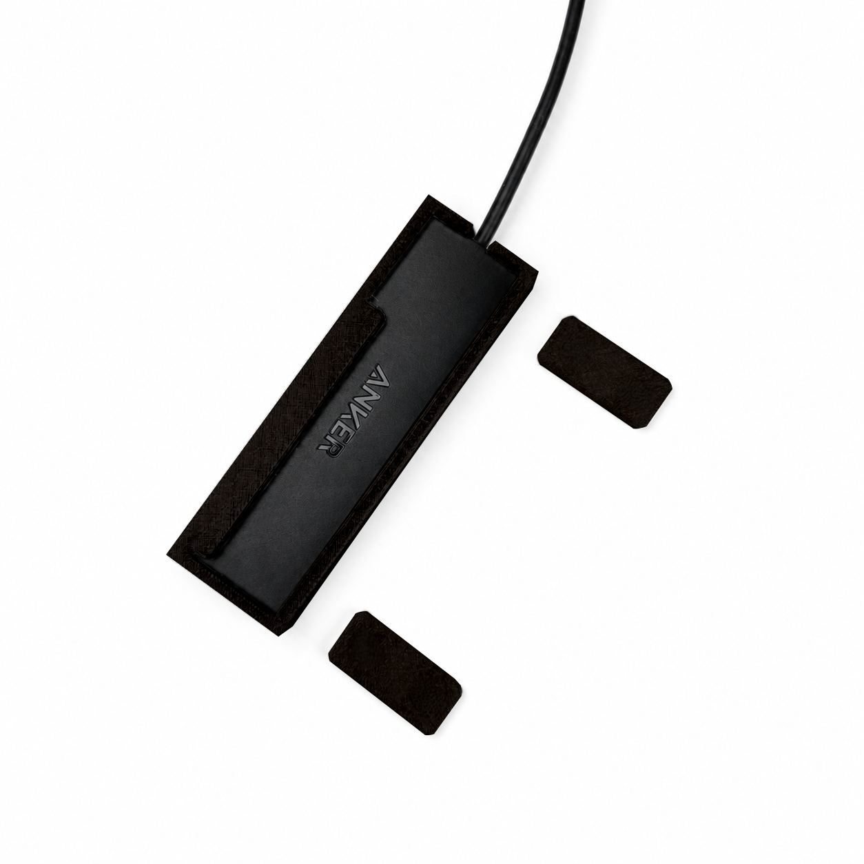 Top view of black HubMount magnetic case holding an Anker USB hub, with adhesive magnetic feet positioned beside it.