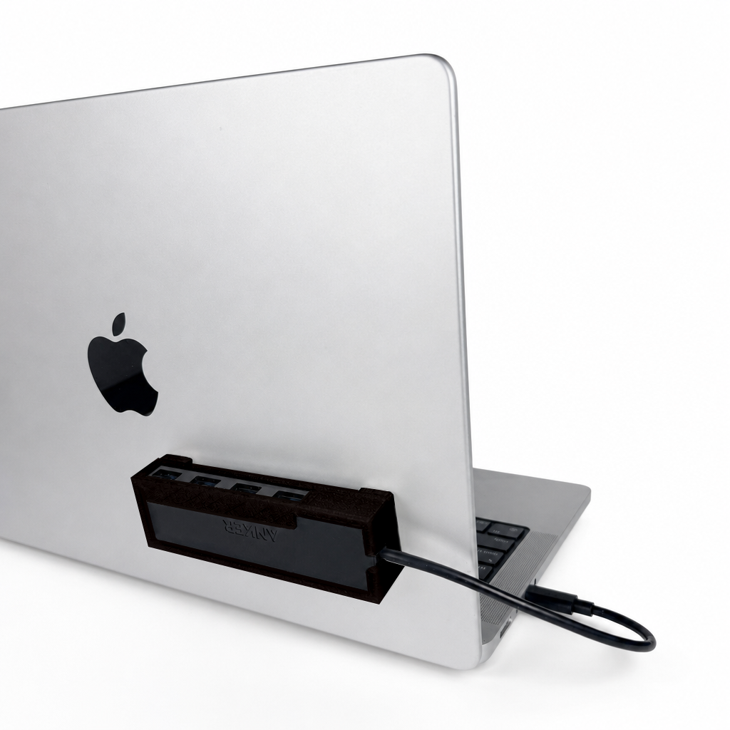 Black HubMount holding an Anker USB hub, securely attached to an open MacBook lid at a 45-degree angle.