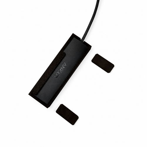 Top view of black HubMount magnetic case holding an Anker USB hub, with adhesive magnetic feet positioned beside it.