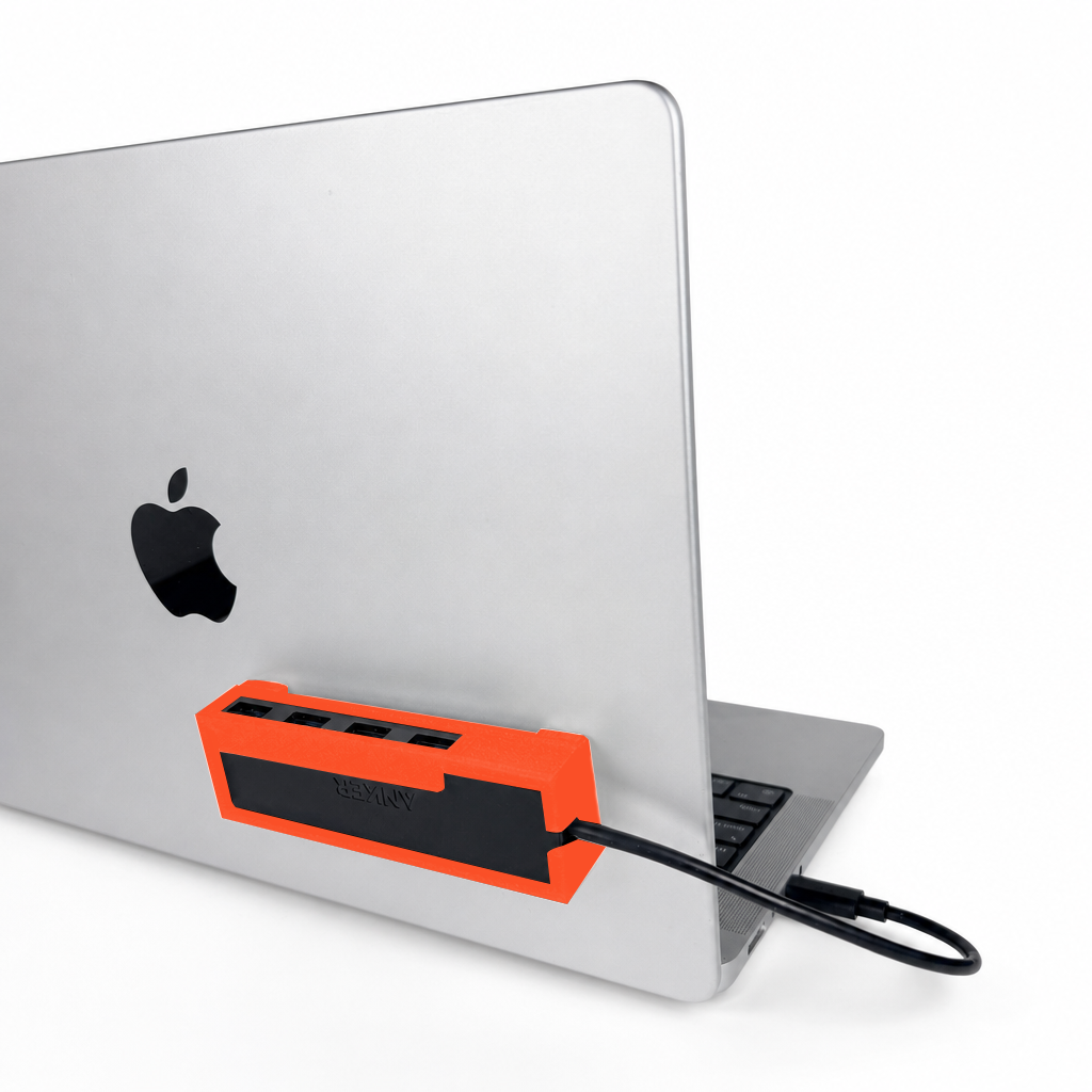 Orange-red HubMount holding an Anker USB hub, securely attached to an open MacBook lid at a 45-degree angle.