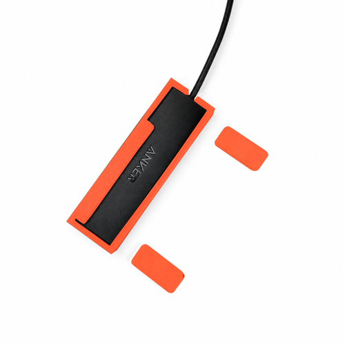 Top view of orange-red HubMount magnetic case holding an Anker USB hub, with adhesive magnetic feet positioned beside it.